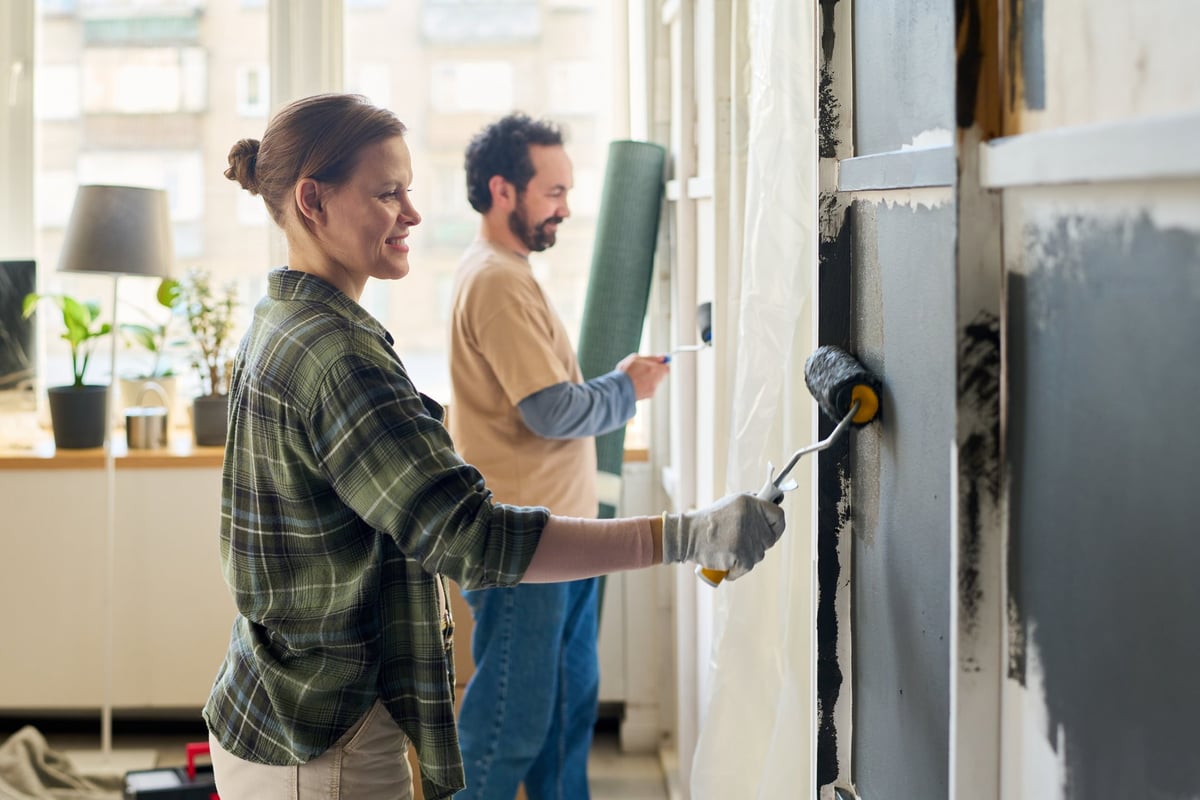 Couple painting living room wall during home renovation project