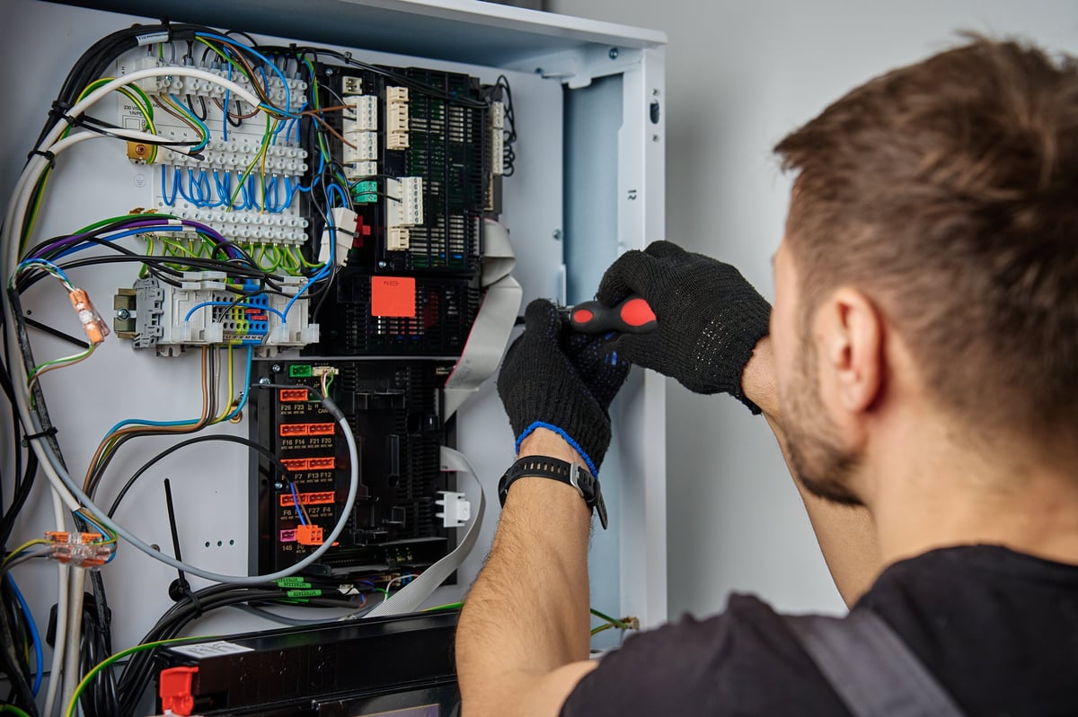 Professional electrician working on electrical wiring and control panel